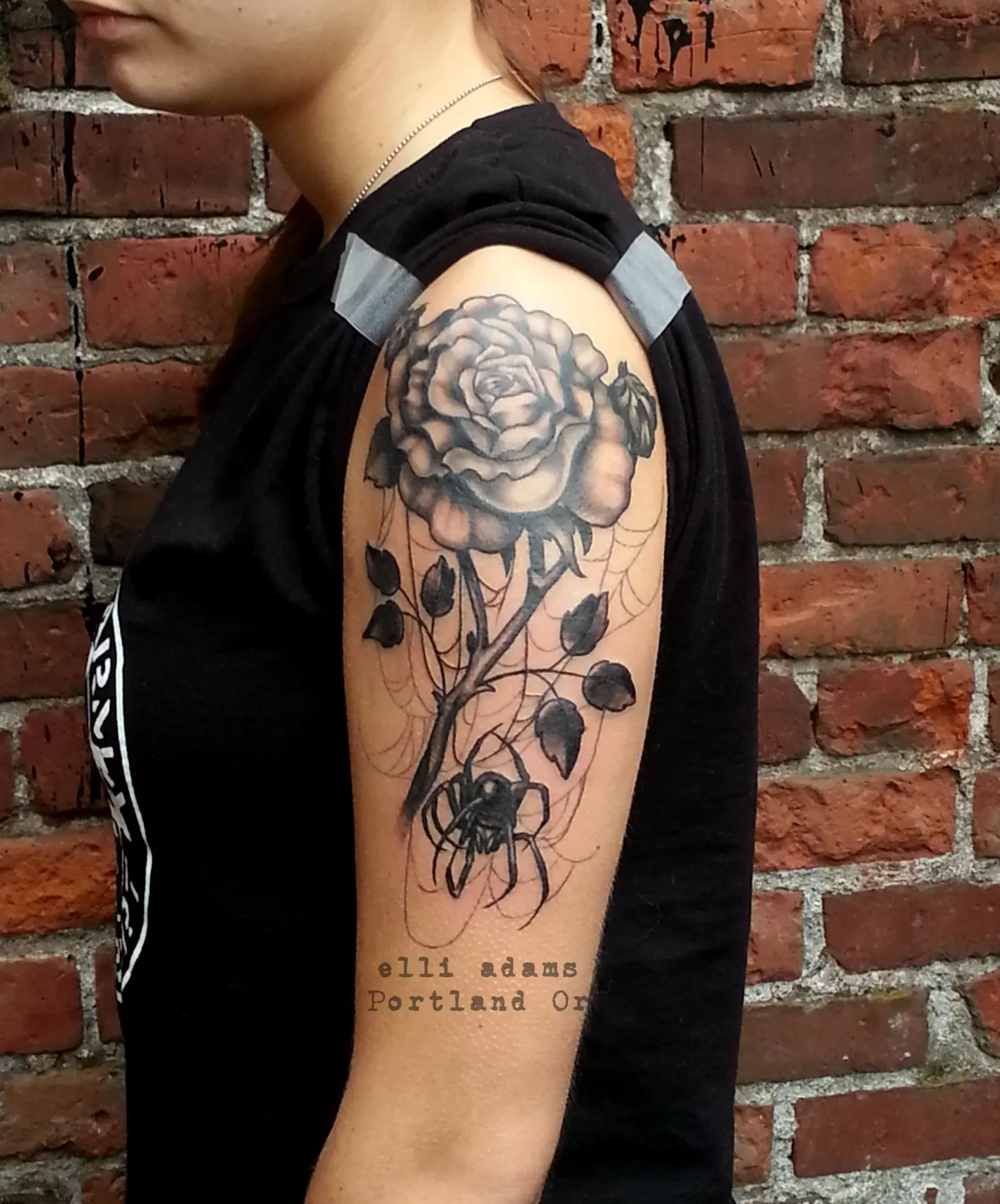 Blackwork tattoo of rose and spider on upper arm by Elli Adams, tattoo artist in Portland, Oregon