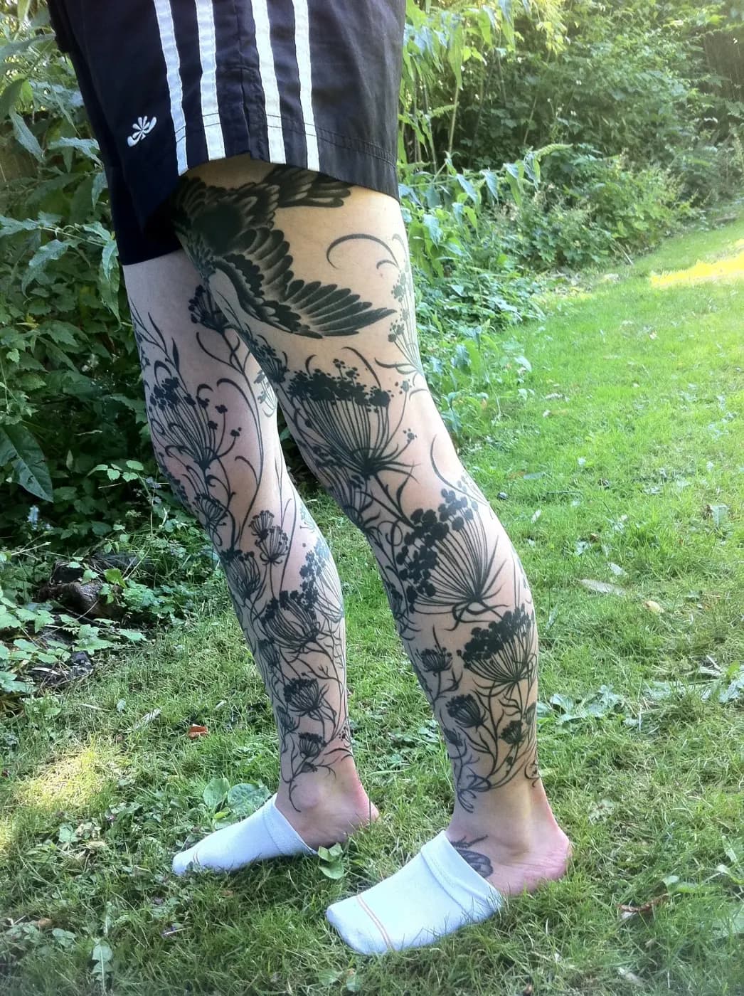 Illustrative tattoo of flowers and botanical on leg sleeve by Lewis Hess, tattoo artist in Portland, Oregon
