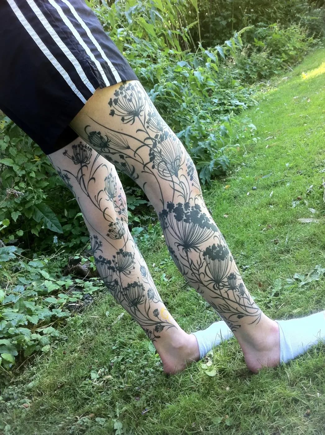 Blackwork tattoo of wildflowers and stems on leg sleeve by Lewis Hess, tattoo artist in Portland, Oregon