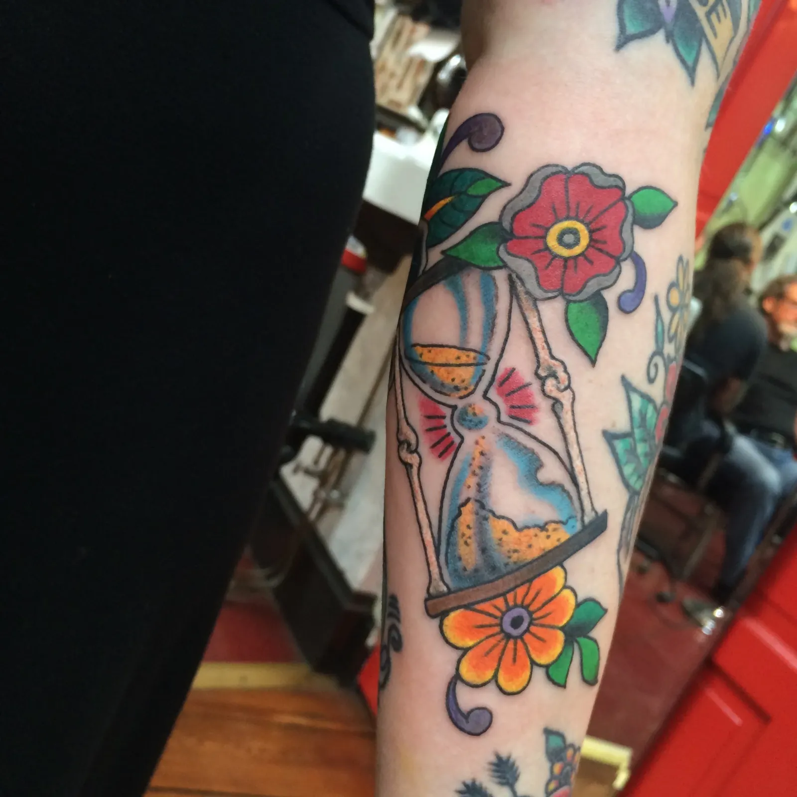 Traditional tattoo of hourglass and flowers on forearm by Mav Mess, tattoo artist in Portland, Oregon