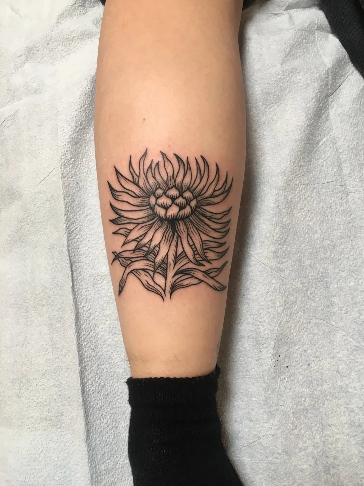 Blackwork tattoo of sunflower on calf by Riversteeth, tattoo artist in Portland, Oregon