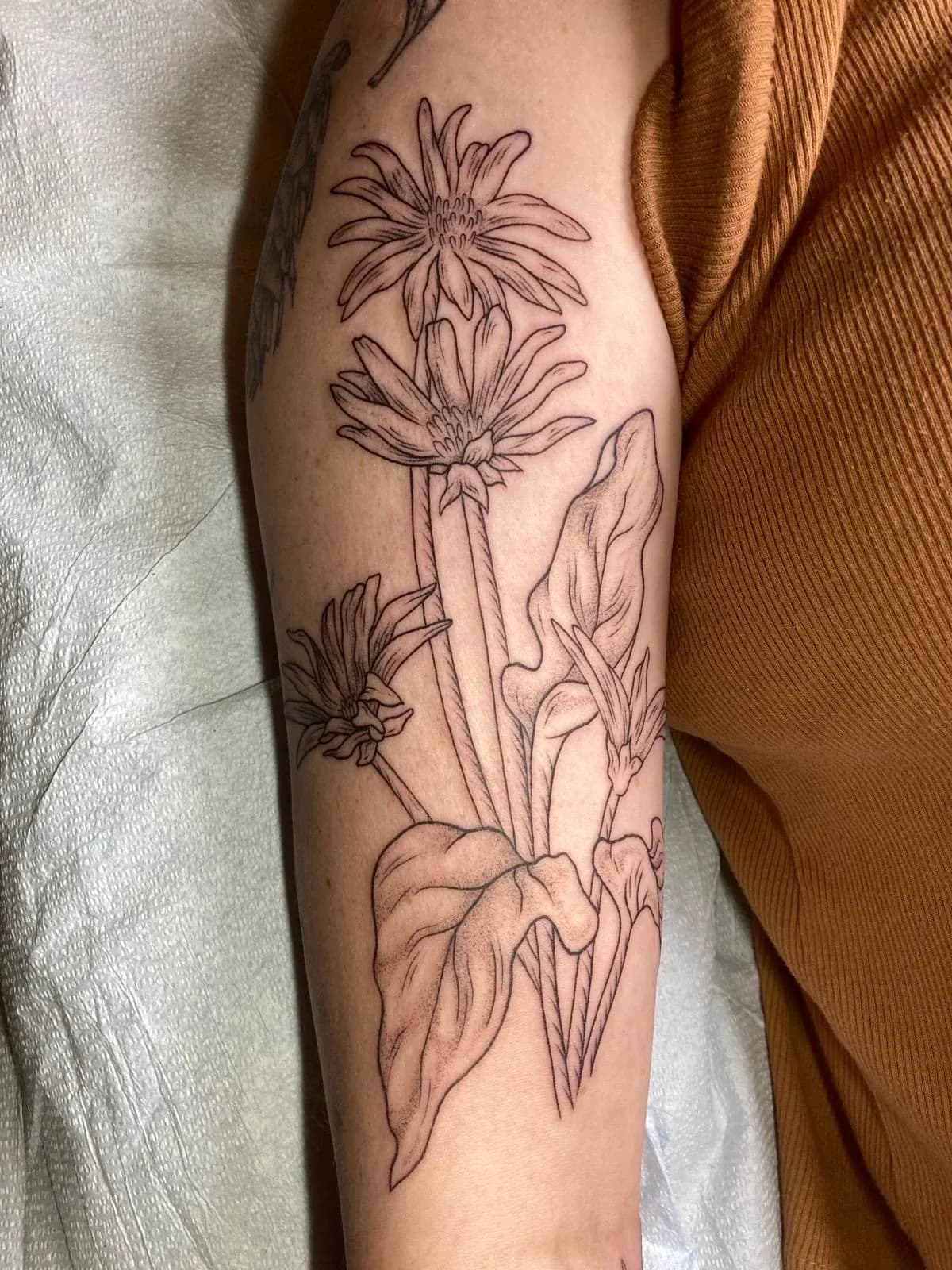Fine-line tattoo of flowers and hand on forearm by Riversteeth, tattoo artist in Portland, Oregon