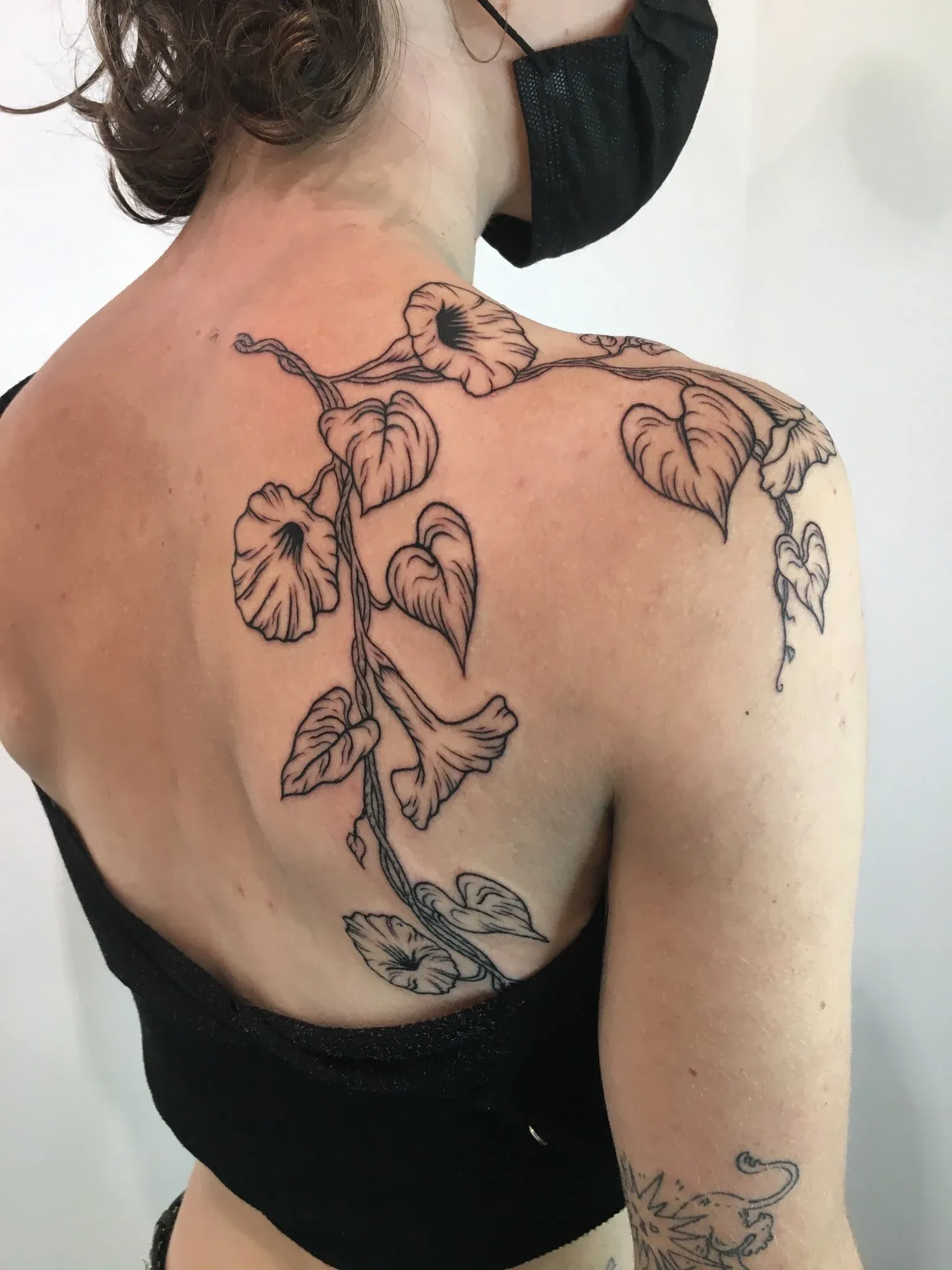 Illustrative tattoo of flowers and vine on back by Riversteeth, tattoo artist in Portland, Oregon