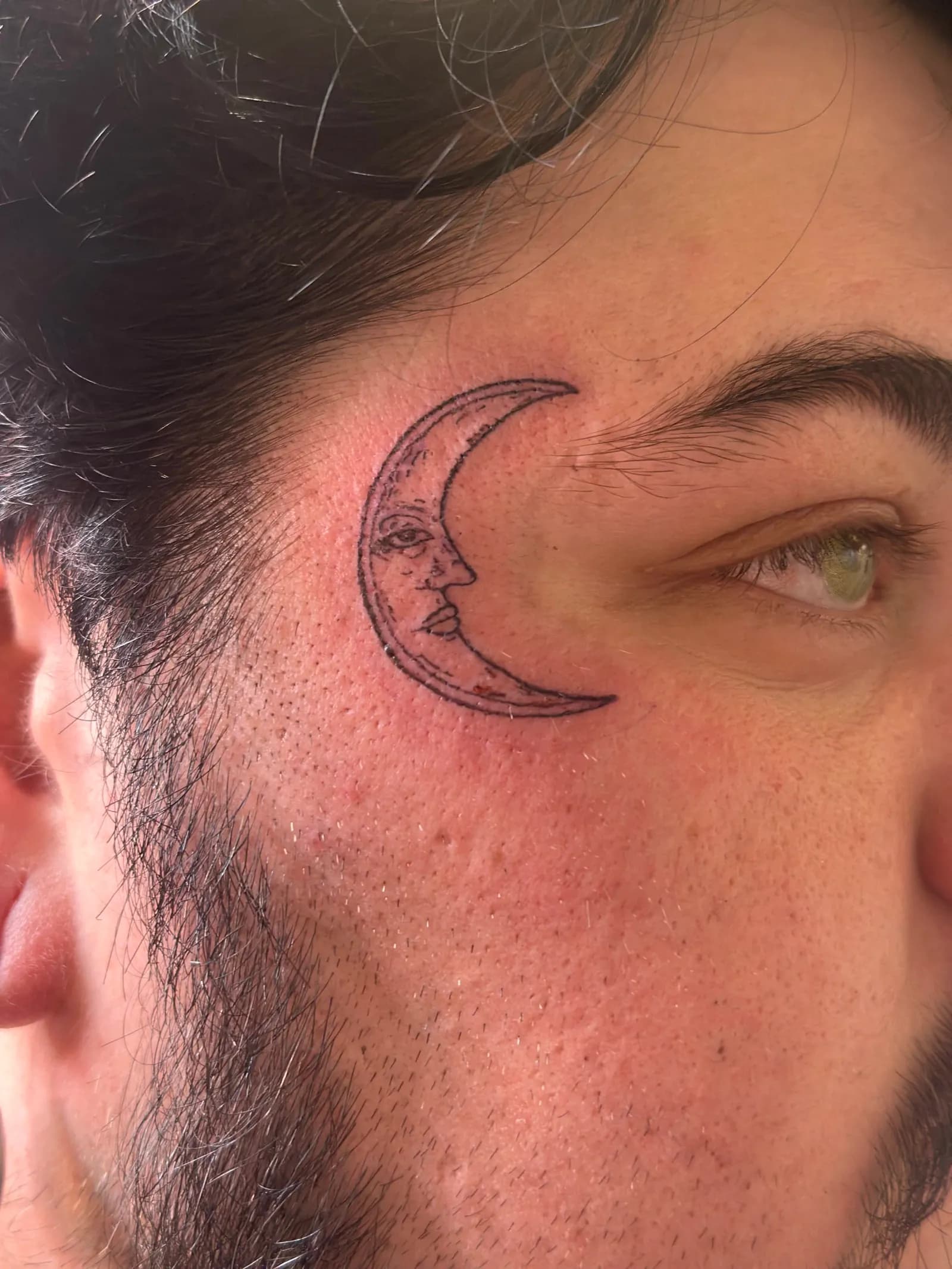 Fine-line tattoo of crescent moon on face by Sadie, tattoo artist in Portland, Oregon