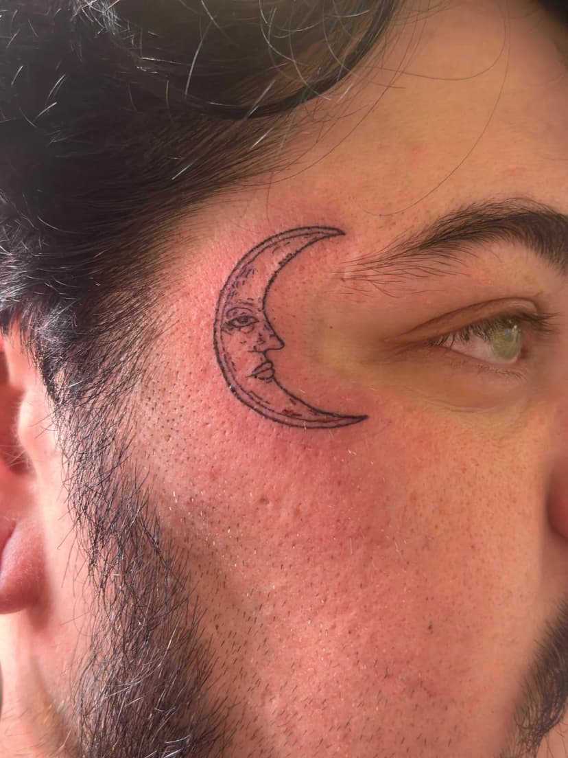 Fine-line tattoo of crescent moon on face by Sadie, tattoo artist in Portland, Oregon