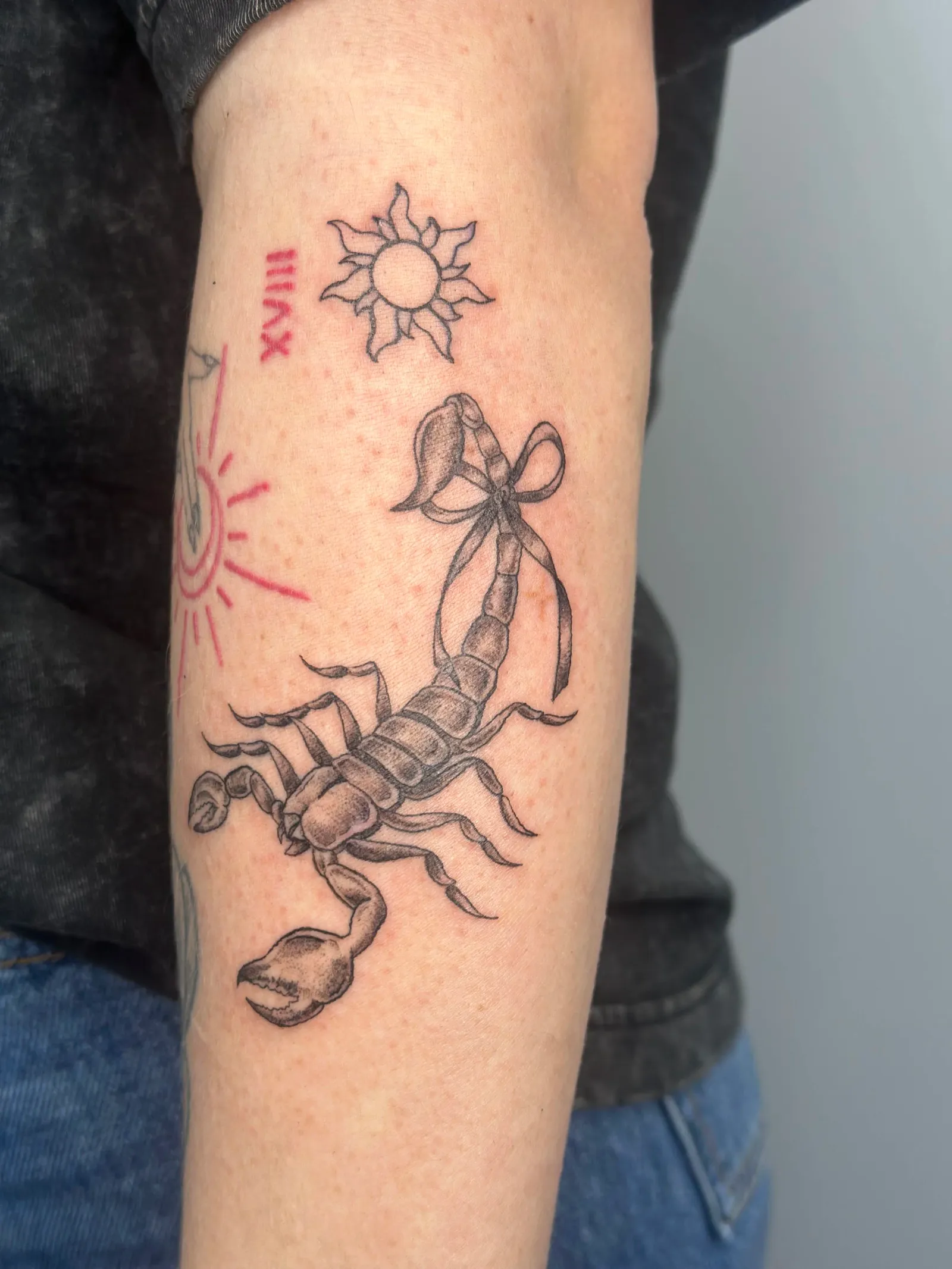 Fine-line tattoo of scorpion and sun on forearm by Sadie, tattoo artist in Portland, Oregon