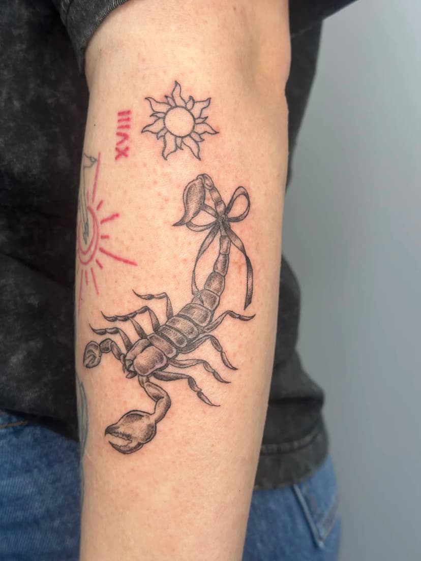 Fine-line tattoo of scorpion and sun on forearm by Sadie, tattoo artist in Portland, Oregon